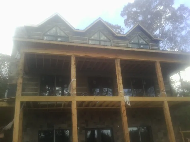 Dormers and porch framing on a large log home under construction — Roof Coating work by our crew in Washburn